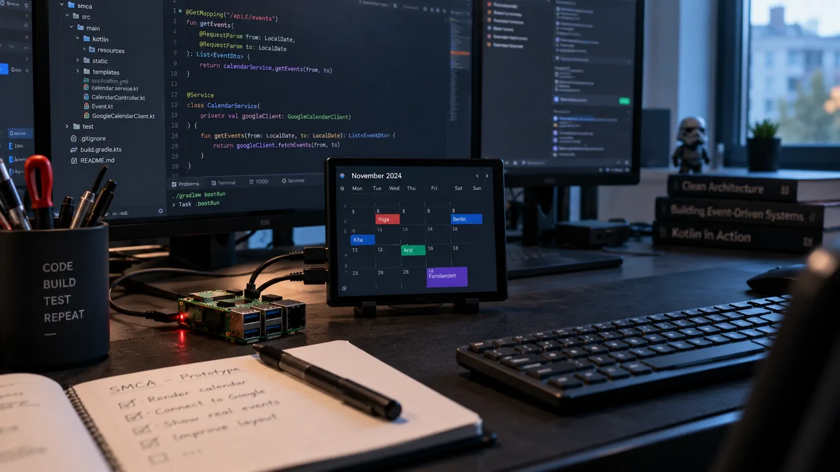 A Raspberry Pi and a small calendar display on a desk in front of code on a monitor.